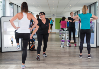 Frauen trainieren in einem Mrs.Sporty Fitnessstudio und werden von Trainierinnen unterstützt