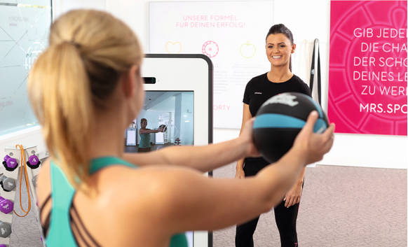 Mrs.Sporty Fitnesstrainerin und Mitglied beim Training am digitalen Smarttrainer